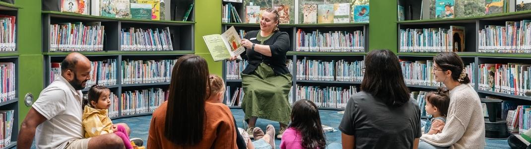Librarian reading a story to children and parents